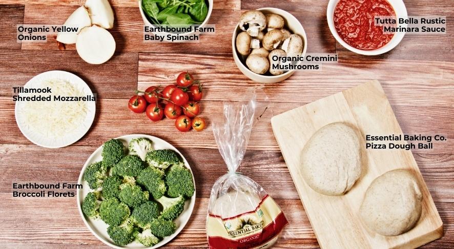 Ingredients for a veggie pizza spread on wooden board